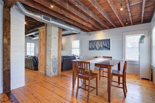 dining space with wooden walls, wood ceiling, and light wood-type flooring