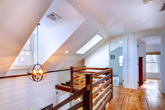 additional living space featuring visible vents, plenty of natural light, light wood-style flooring, and a chandelier