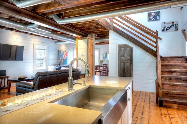 kitchen featuring a sink, open floor plan, white cabinetry, light wood-style floors, and light countertops