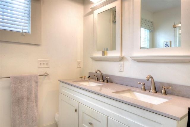 bathroom with double vanity, toilet, and a sink