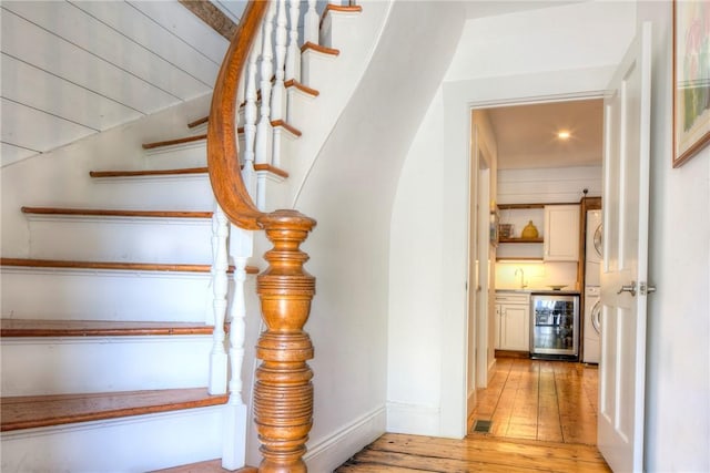 stairway with baseboards, visible vents, indoor wet bar, hardwood / wood-style flooring, and wine cooler