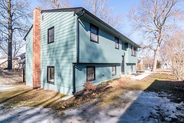 view of side of home with fence and a chimney