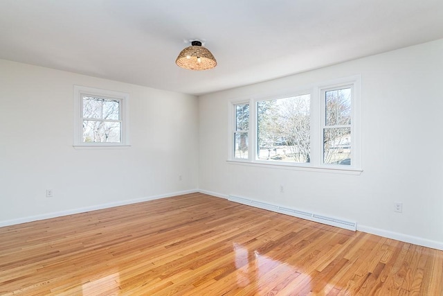 empty room featuring a baseboard radiator, a healthy amount of sunlight, light wood-style flooring, and baseboards