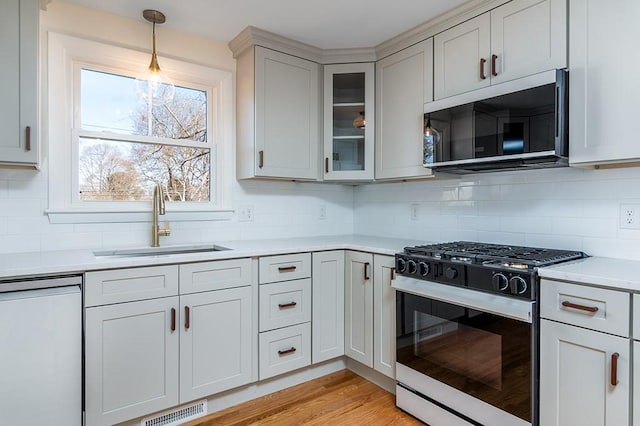 kitchen with range with gas cooktop, light countertops, visible vents, a sink, and dishwasher