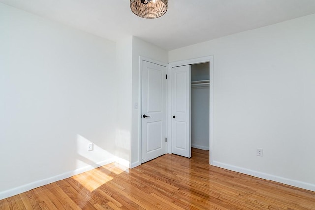 unfurnished bedroom with light wood-style floors, a closet, and baseboards