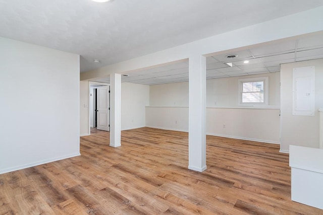 below grade area with a drop ceiling, light wood-style flooring, and baseboards