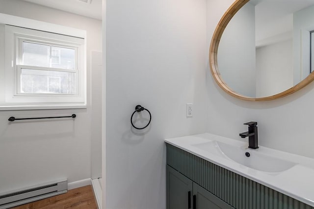 bathroom with baseboard heating, wood finished floors, vanity, and baseboards