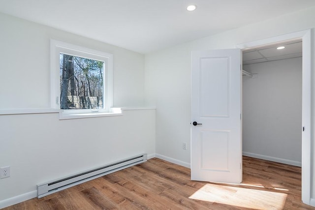 unfurnished bedroom with a baseboard radiator, recessed lighting, wood finished floors, baseboards, and a closet