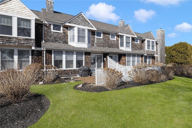 view of front of property featuring a shingled roof, a chimney, fence, and a front lawn