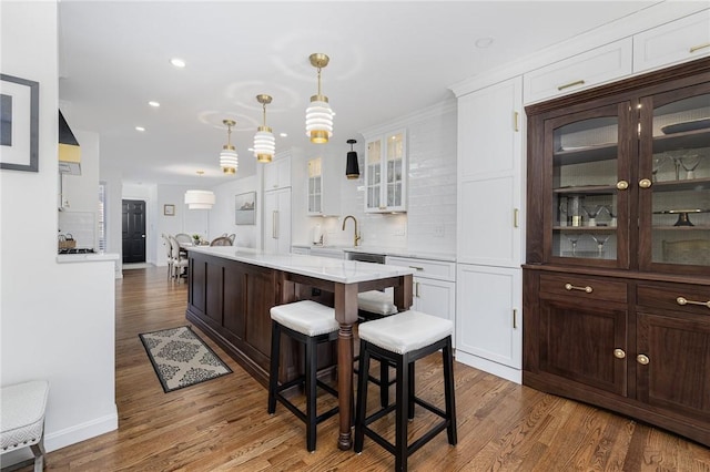 kitchen with dark wood-style floors, light countertops, glass insert cabinets, white cabinets, and dark brown cabinetry