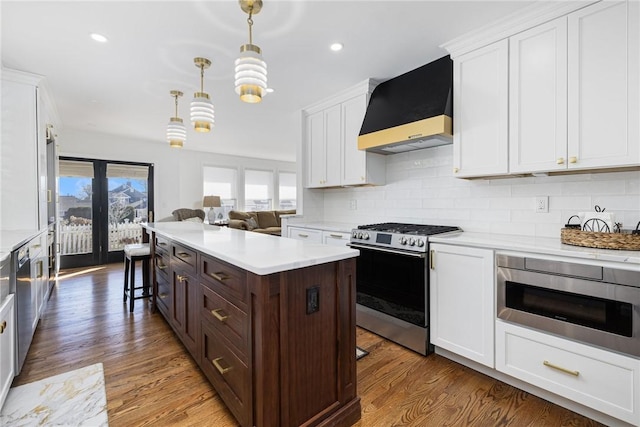 kitchen featuring white cabinets, stainless steel appliances, light countertops, and exhaust hood