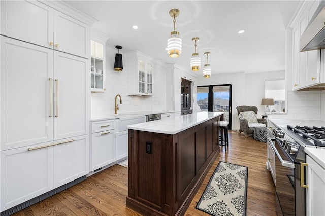 kitchen with wall chimney exhaust hood, dark wood-style flooring, a sink, and gas range