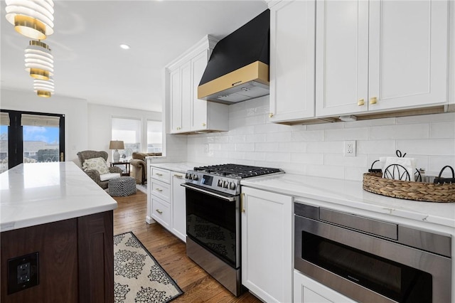 kitchen featuring tasteful backsplash, wall chimney exhaust hood, appliances with stainless steel finishes, dark wood-type flooring, and white cabinetry