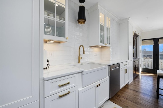 kitchen with light stone counters, a sink, white cabinets, stainless steel dishwasher, and decorative backsplash