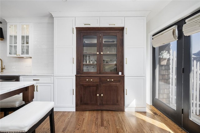 bar featuring light wood finished floors and tasteful backsplash