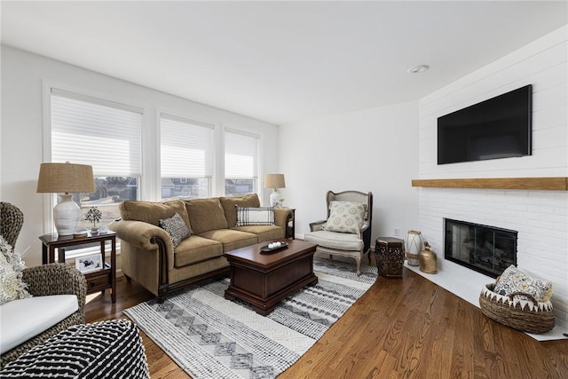 living room featuring a brick fireplace and wood finished floors