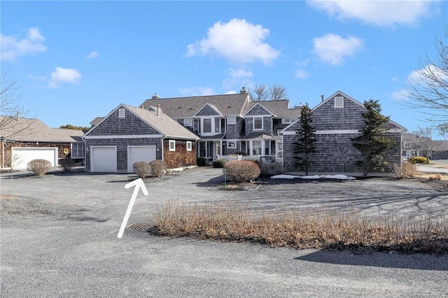 shingle-style home with driveway and an attached garage