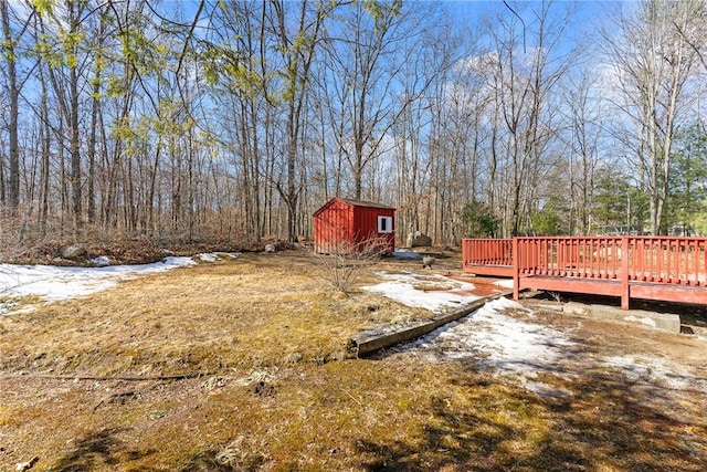 view of yard with a storage shed, a deck, an outdoor structure, and a view of trees