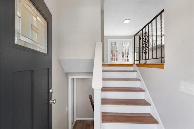 stairs with french doors, wood finished floors, and baseboards