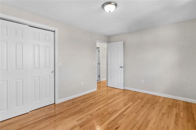 unfurnished bedroom featuring light wood-style floors, baseboards, and a closet