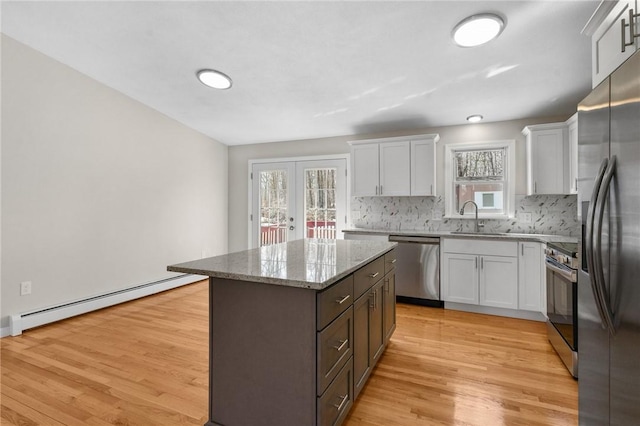 kitchen with a baseboard heating unit, a kitchen island, french doors, appliances with stainless steel finishes, and light wood-type flooring