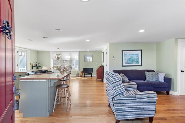 living room with a chandelier, light wood-type flooring, baseboards, and recessed lighting