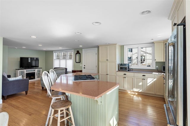 kitchen with light wood finished floors, high quality fridge, a wealth of natural light, and cream cabinetry