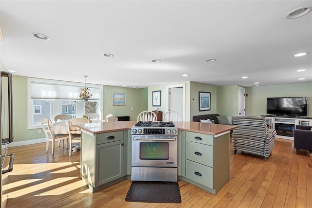 kitchen with high end stove, light wood-style flooring, recessed lighting, a kitchen island, and open floor plan