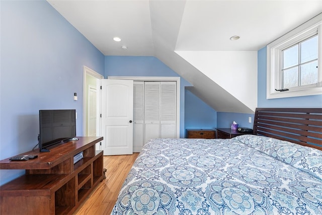 bedroom with lofted ceiling, light wood-style flooring, and a closet