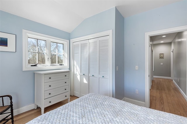 bedroom featuring recessed lighting, a closet, vaulted ceiling, wood finished floors, and baseboards