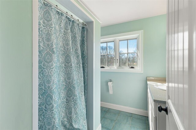 bathroom featuring curtained shower, vanity, baseboards, and tile patterned floors