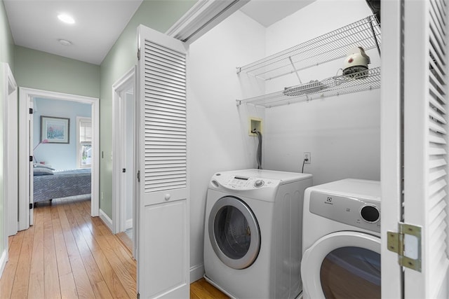 washroom with laundry area, light wood-style flooring, baseboards, and separate washer and dryer