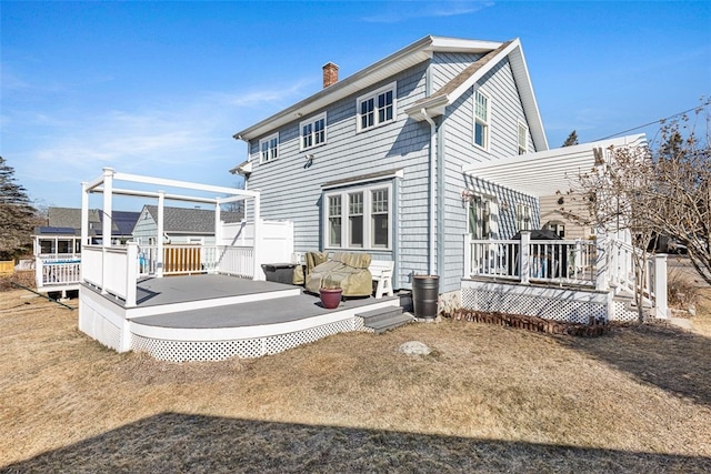 back of house with a chimney, a pergola, and a wooden deck