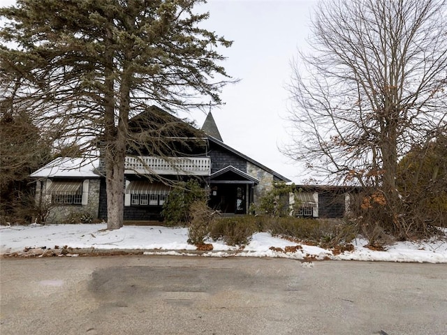 view of front of house with stone siding and a balcony