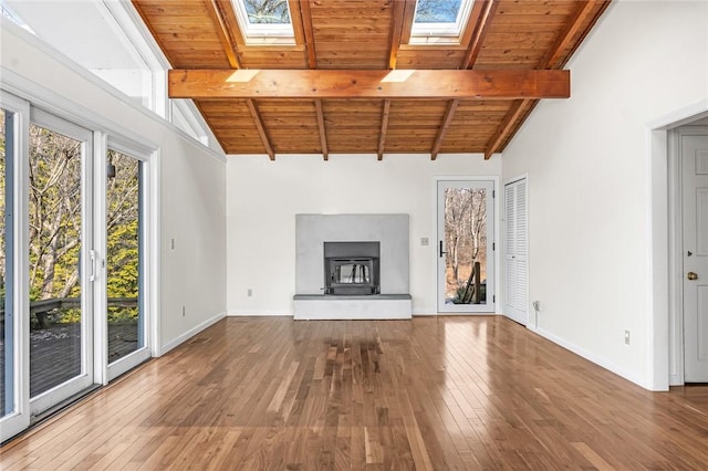 unfurnished living room with lofted ceiling with skylight, wood-type flooring, wooden ceiling, and baseboards