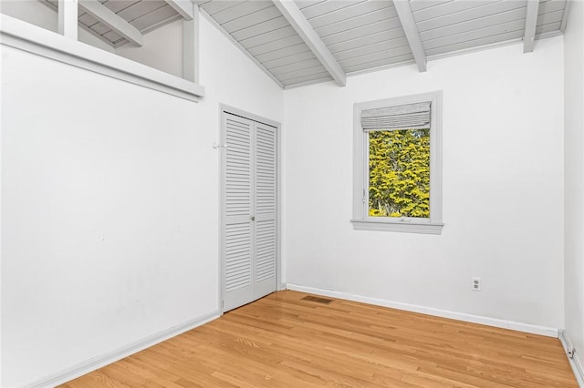 unfurnished bedroom with lofted ceiling with beams, light wood-style flooring, visible vents, and baseboards