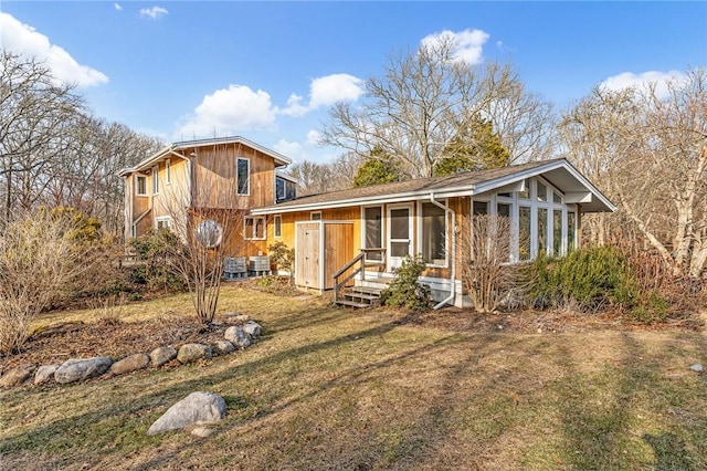 view of front of house with entry steps, a front lawn, and a sunroom