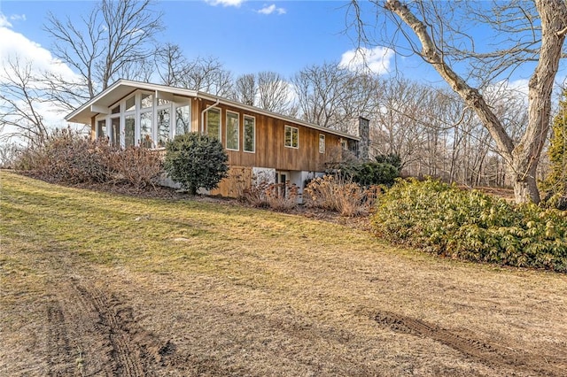 view of side of home featuring a chimney and a lawn