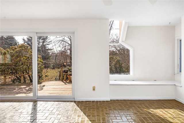 doorway featuring brick floor and baseboards