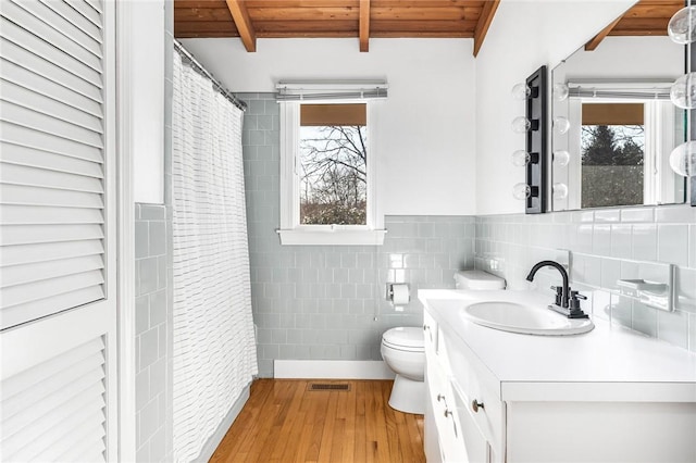 bathroom with toilet, wooden ceiling, beamed ceiling, wood finished floors, and tile walls