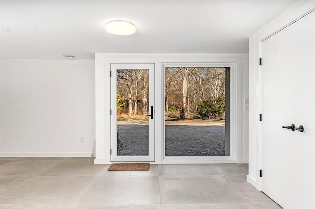 doorway featuring finished concrete flooring, baseboards, and visible vents