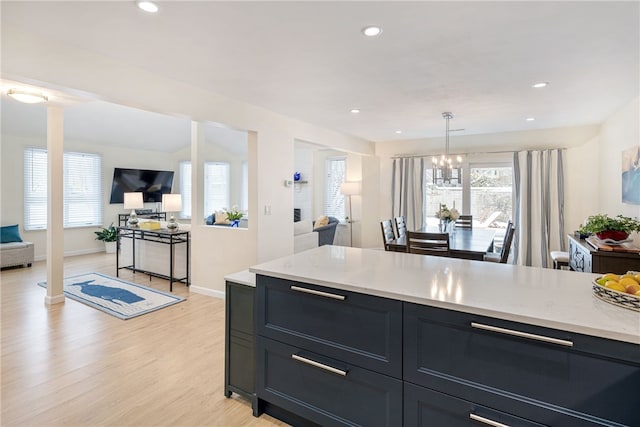 kitchen with baseboards, light wood finished floors, recessed lighting, hanging light fixtures, and open floor plan