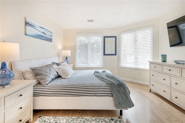 bedroom with light wood-style flooring, baseboards, and visible vents