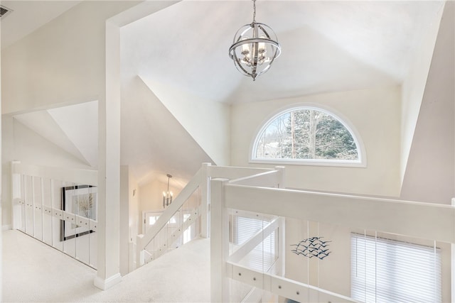 interior space featuring visible vents, an upstairs landing, high vaulted ceiling, an inviting chandelier, and carpet flooring