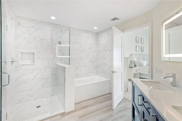 bathroom with a garden tub, a stall shower, wood finished floors, ensuite bath, and a sink