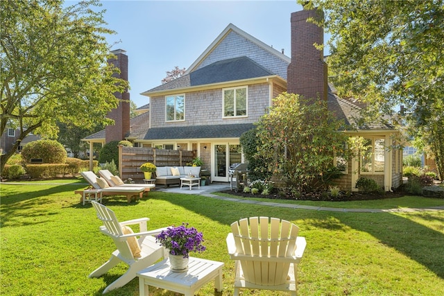 rear view of house with an outdoor living space, a shingled roof, a chimney, a yard, and a patio