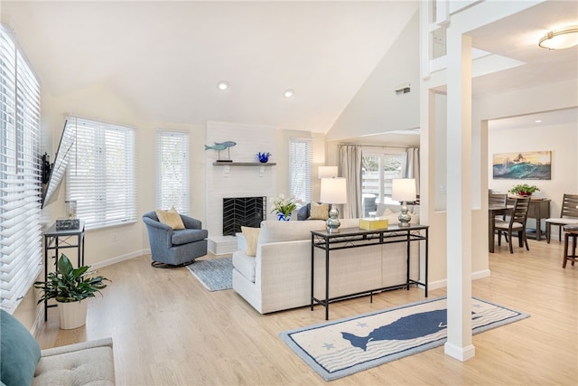 living room featuring visible vents, high vaulted ceiling, wood finished floors, a fireplace, and baseboards