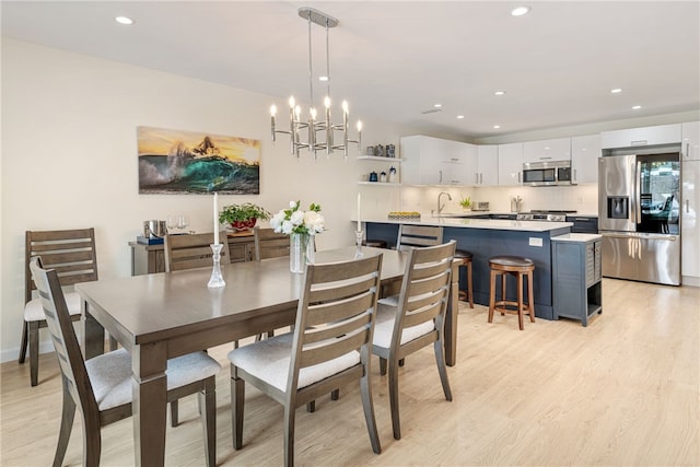 dining area with light wood finished floors, recessed lighting, and an inviting chandelier