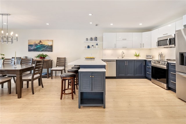 kitchen featuring white cabinets, light wood-style flooring, tasteful backsplash, and stainless steel appliances