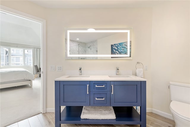 ensuite bathroom with a sink, baseboards, toilet, and double vanity